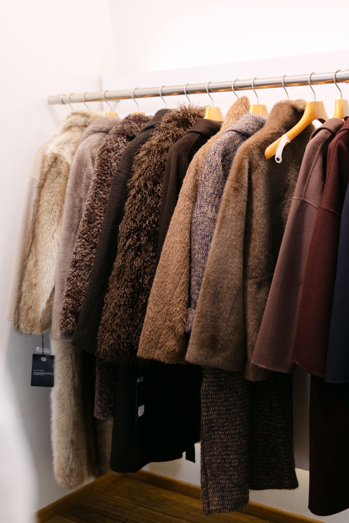 Kleiderstange mit Fell- und Shearling-Mänteln in Beige- und Brauntönen als Sinnbild für eine elegante Garderobe in Linz bei ZWEI auf der Spittelwiese